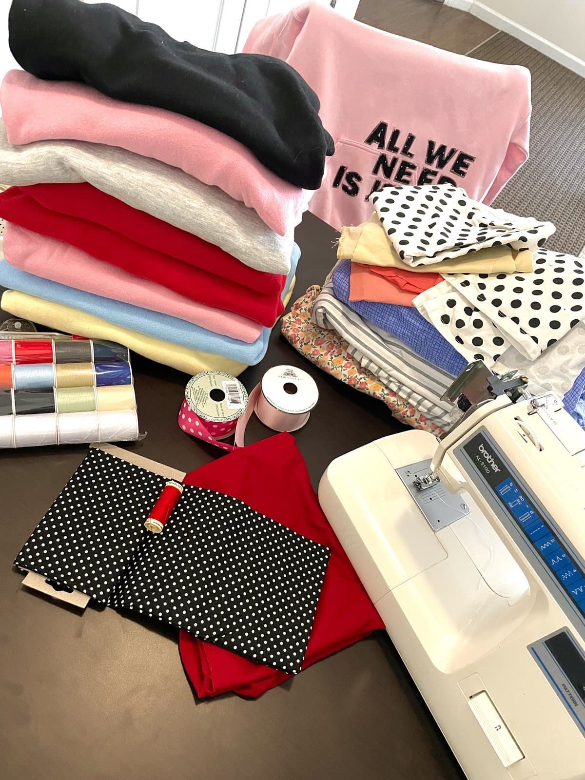 Mya's studio — sewing machine, thread spools, fabric stacks